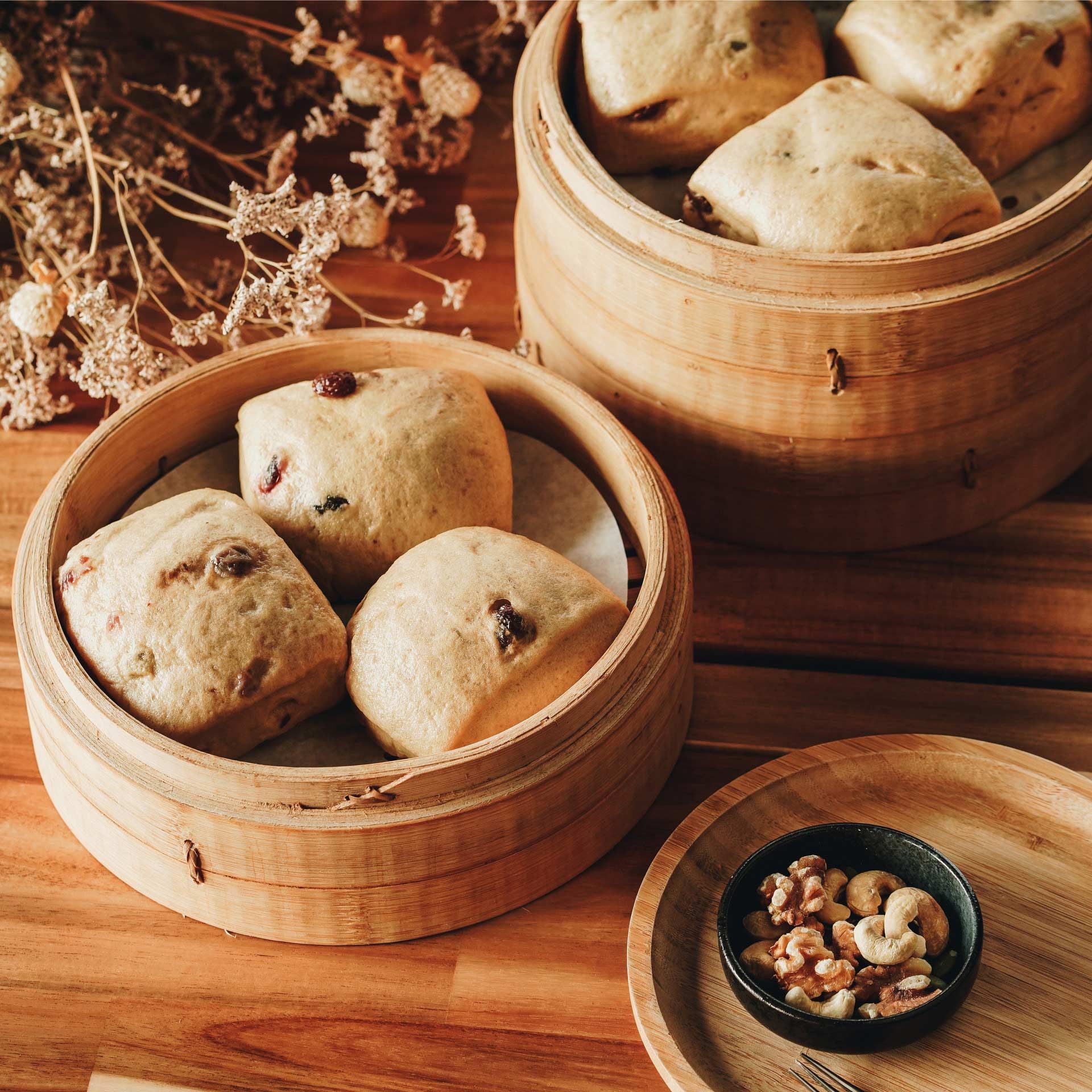 Two wooden steamers filled with bread and nuts on a wooden table