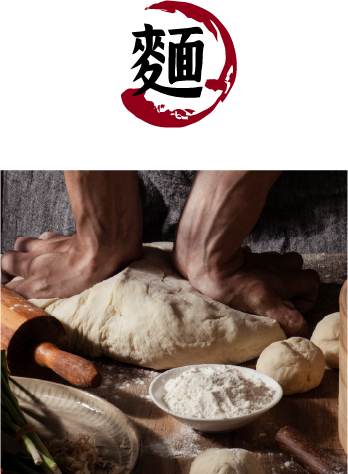 A person kneading dough with a rolling pin and a bowl of flour