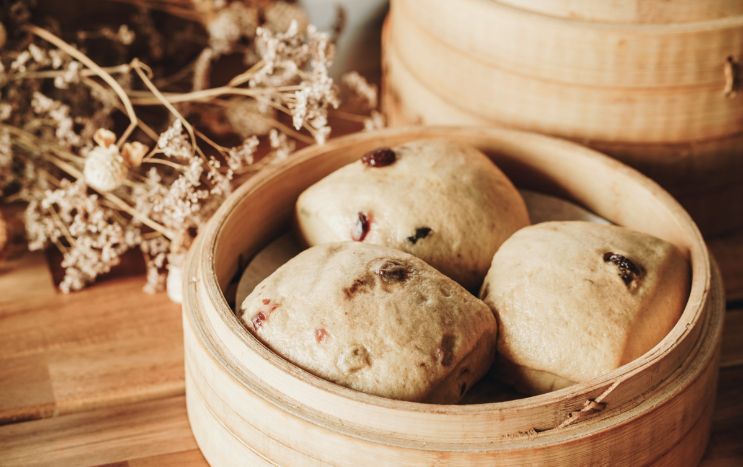 A wooden bamboo steamer filled with dim sum on a wooden table.