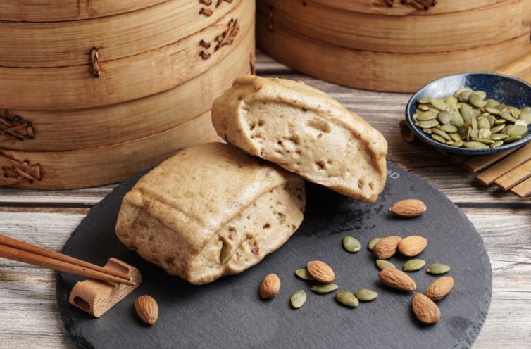 A wooden bamboo steamer filled with dim sum on a wooden table.