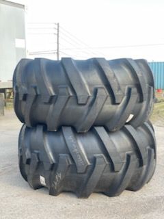 Two black tractor tires stacked on top of each other outside.