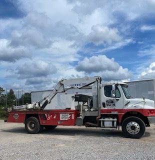 White and red service truck with a crane against a cloudy sky.