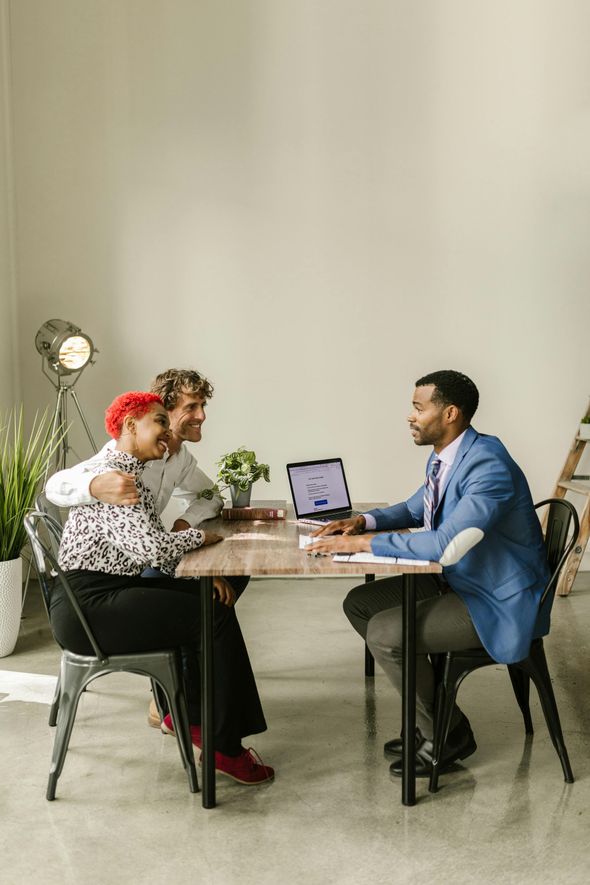 A man is sitting at a table talking to a couple.