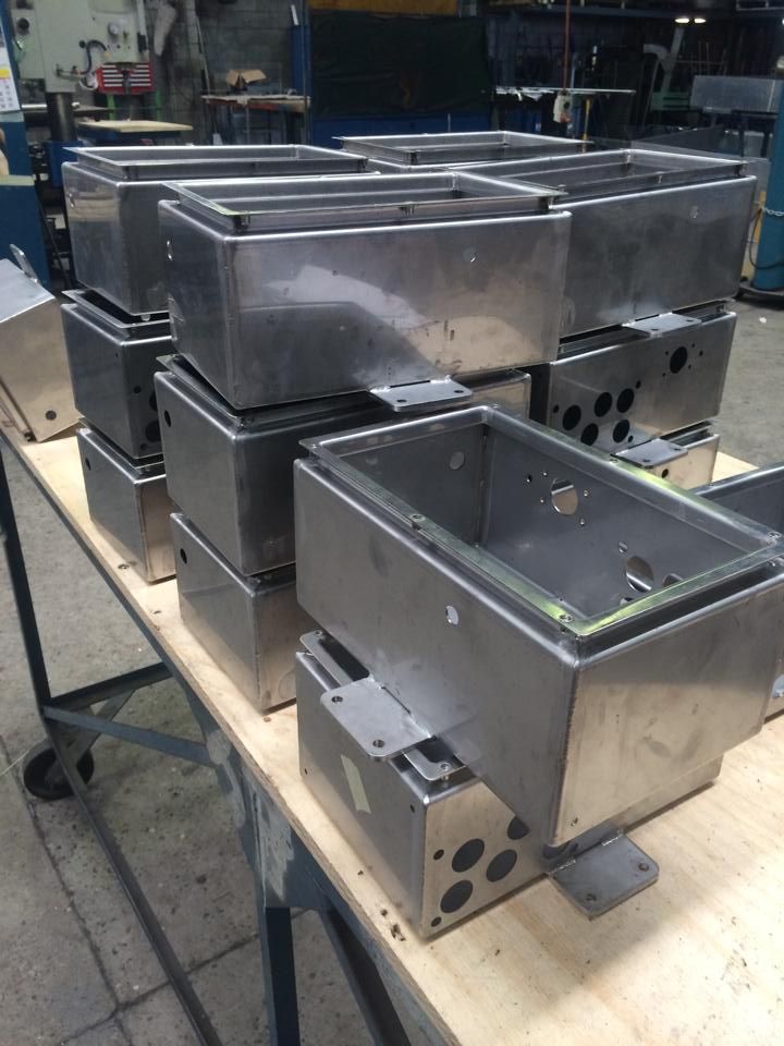 A bunch of stainless steel boxes are stacked on top of each other on a wooden table.