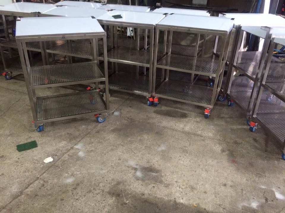 A bunch of stainless steel shelves with wheels on the floor.