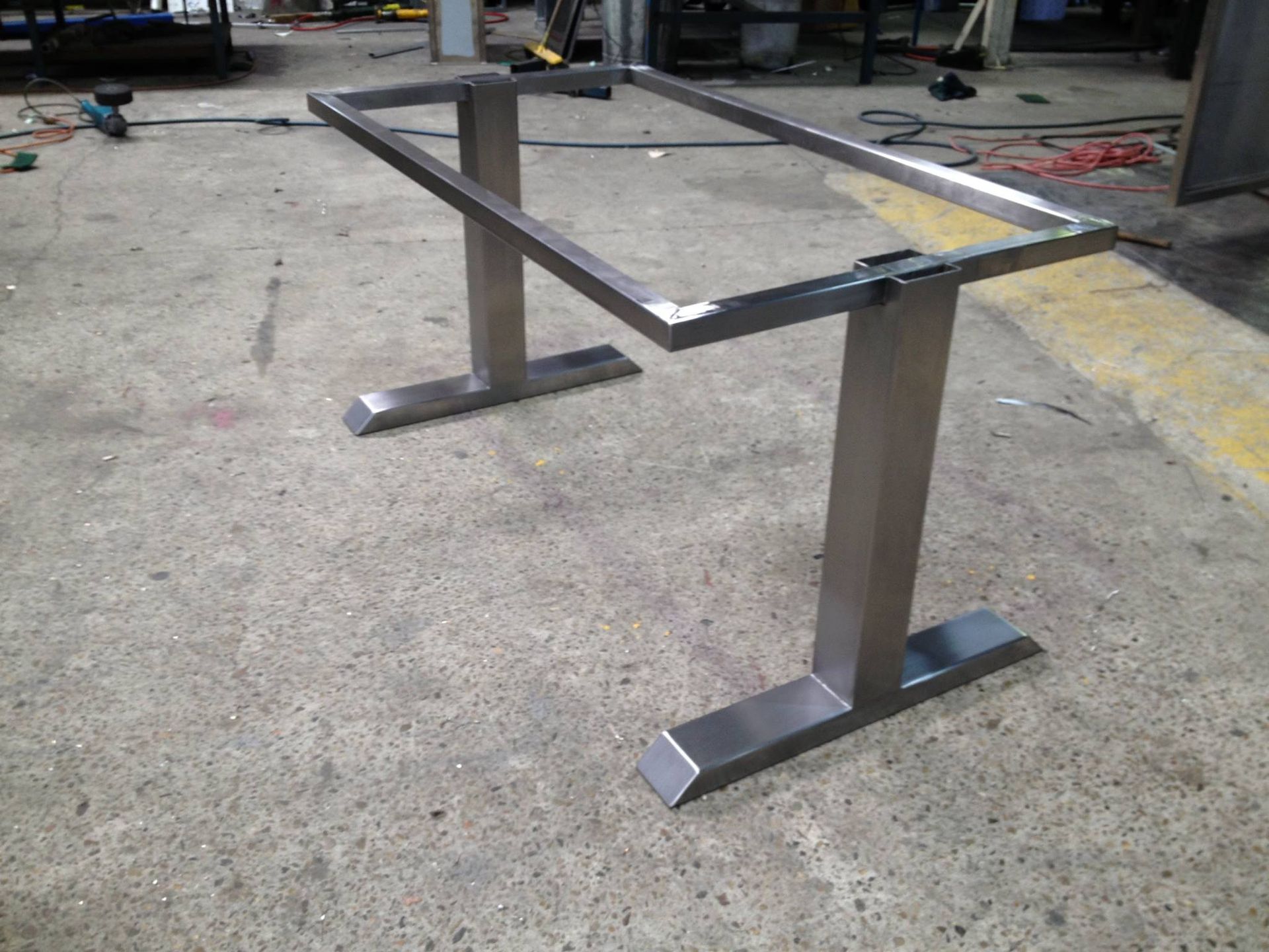 A stainless steel table frame is sitting on a concrete floor.