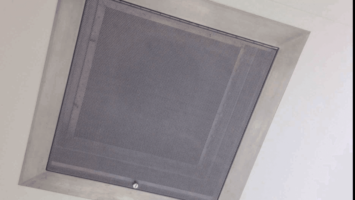 A close up of a ceiling vent with a mesh cover on it.