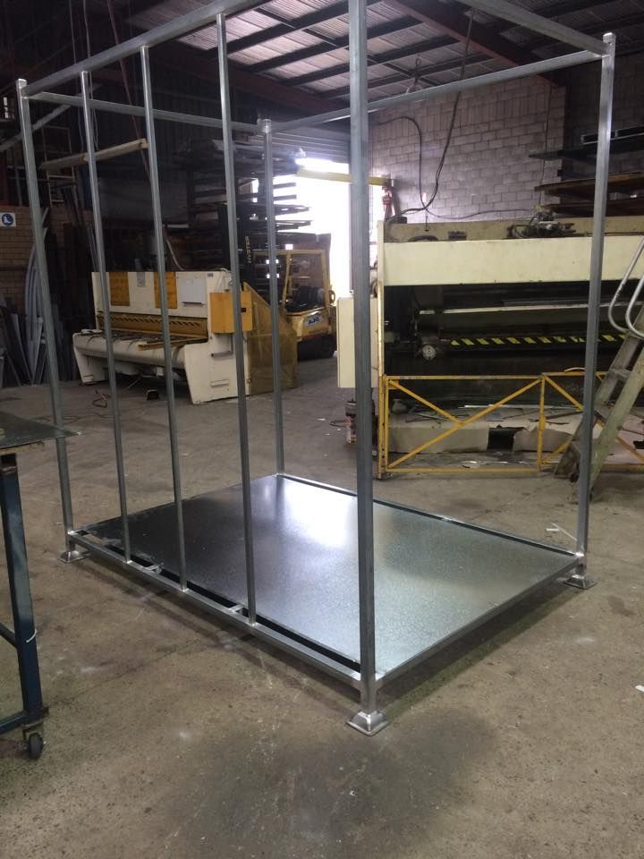 A metal structure is sitting on the ground in a factory.