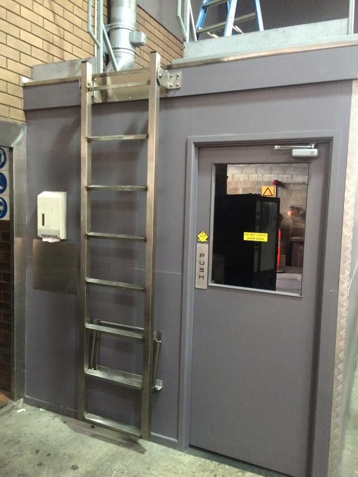 A ladder is attached to the side of a building next to a door.