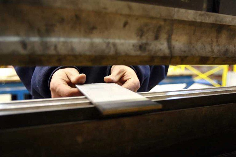 A person is cutting a piece of metal with a machine.