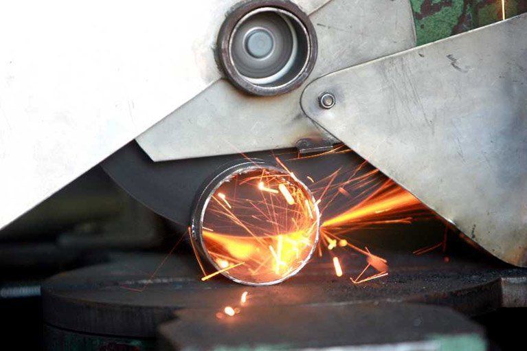 A machine is cutting a metal pipe with sparks coming out of it.