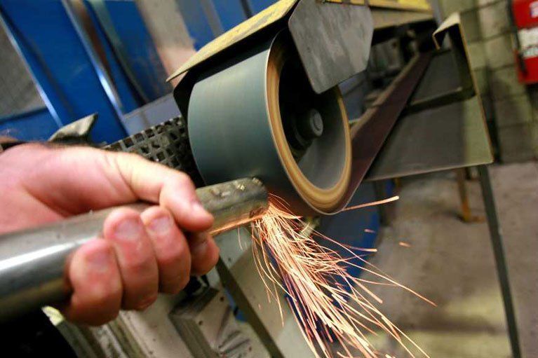 A person is grinding a piece of metal on a machine.