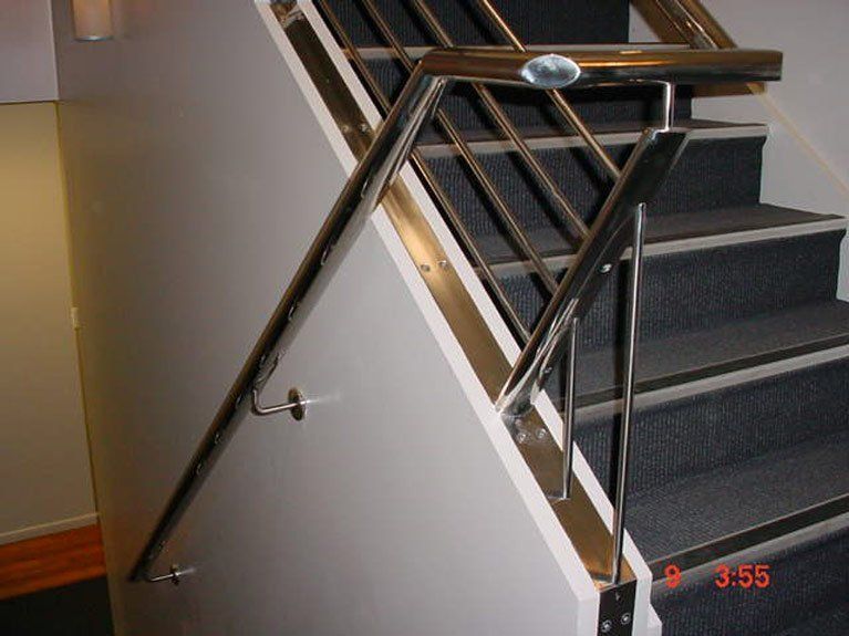 A staircase with a stainless steel railing and carpeted steps