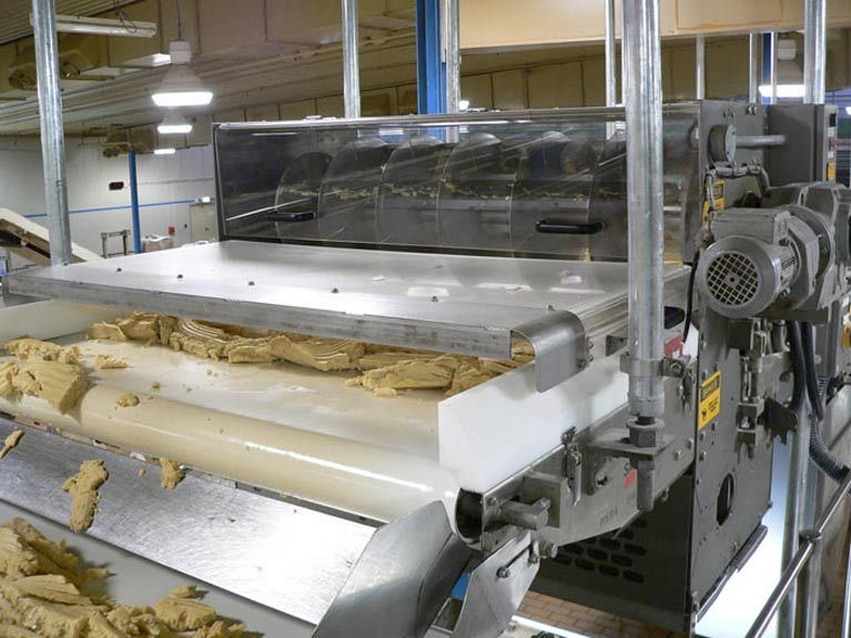 A conveyor belt filled with dough is in a factory.