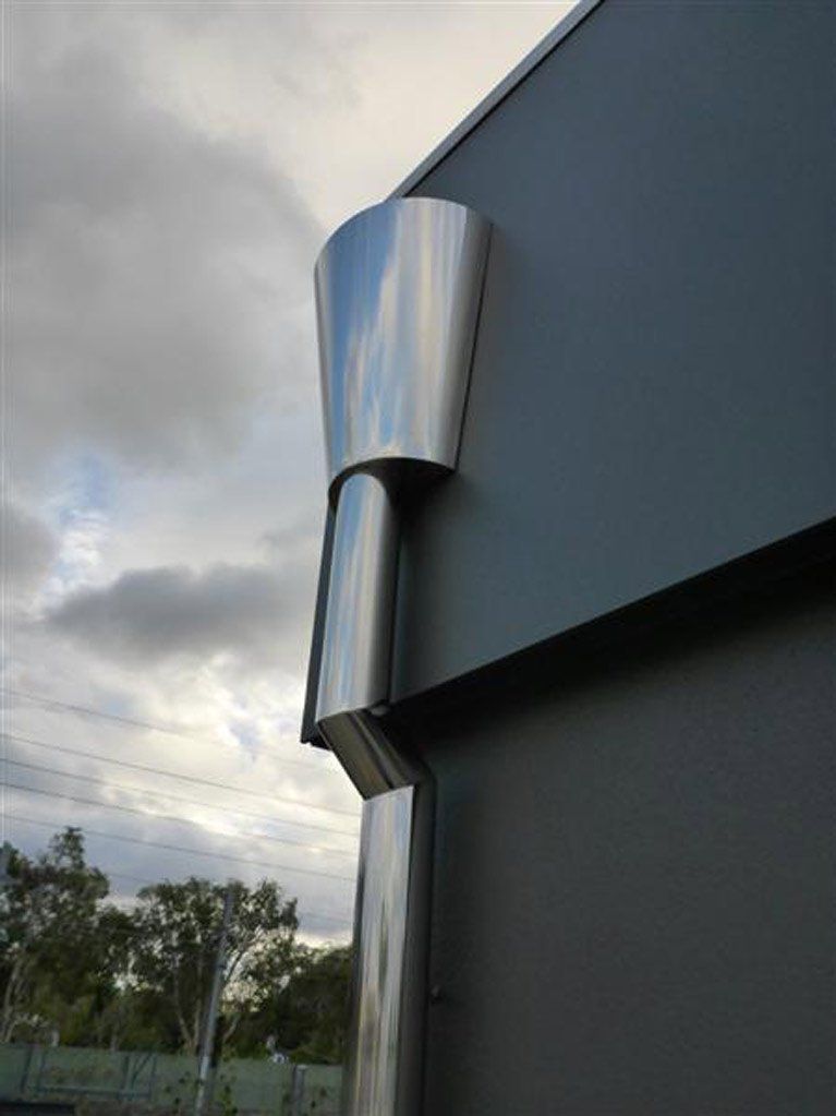A stainless steel pipe is attached to the side of a building.