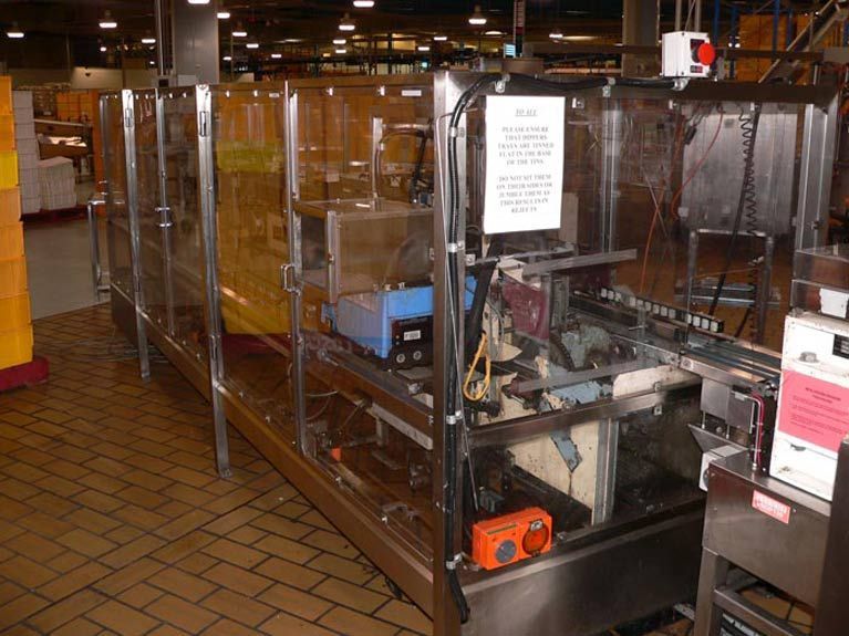A row of stainless steel containers are lined up in a warehouse.