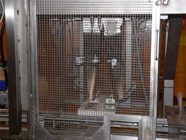 A stainless steel fence is surrounding a machine in a factory.