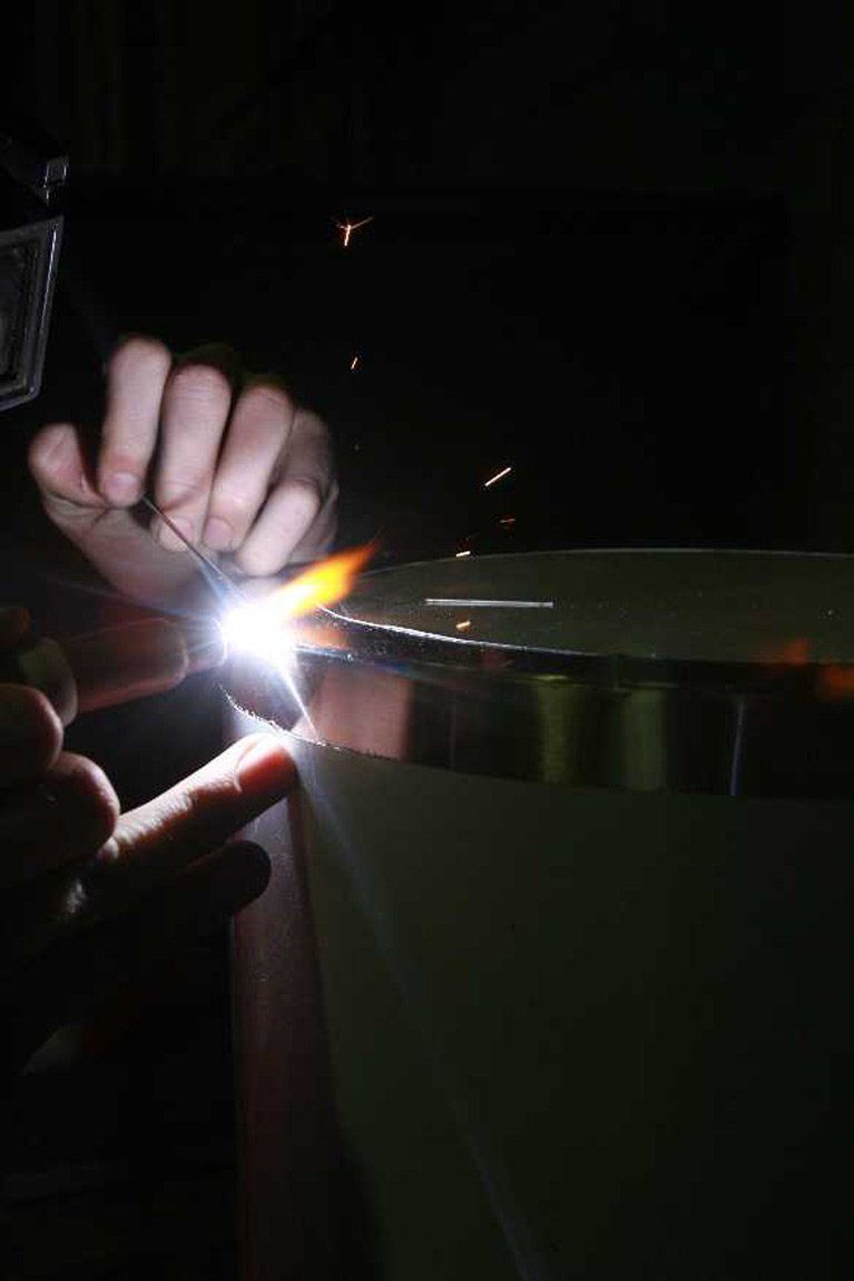 A person is welding a piece of metal in the dark.