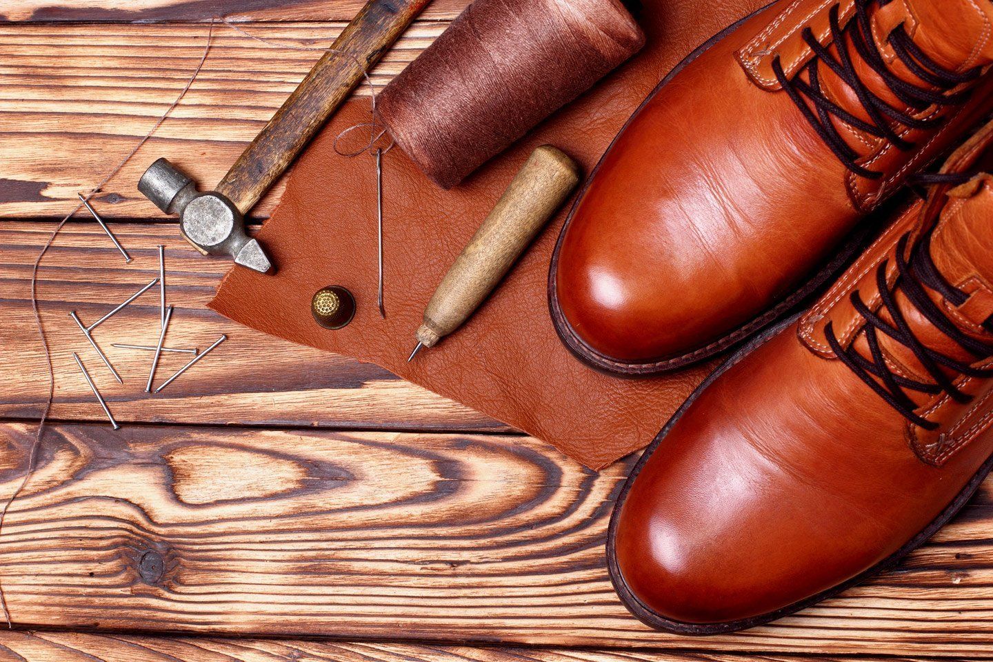 attrezzi da calzolaio e scarpe di pelle su tavolo di legno
