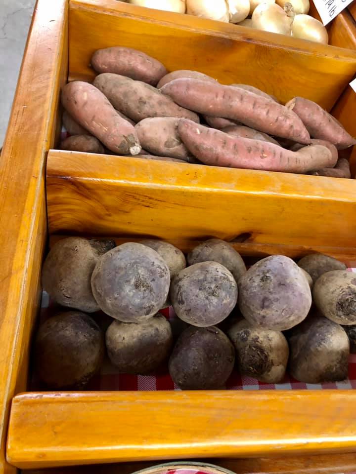 A wooden crate filled with potatoes and sweet potatoes