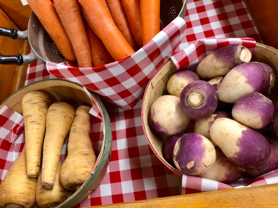 A basket of carrots and a basket of turnips on a checkered table cloth