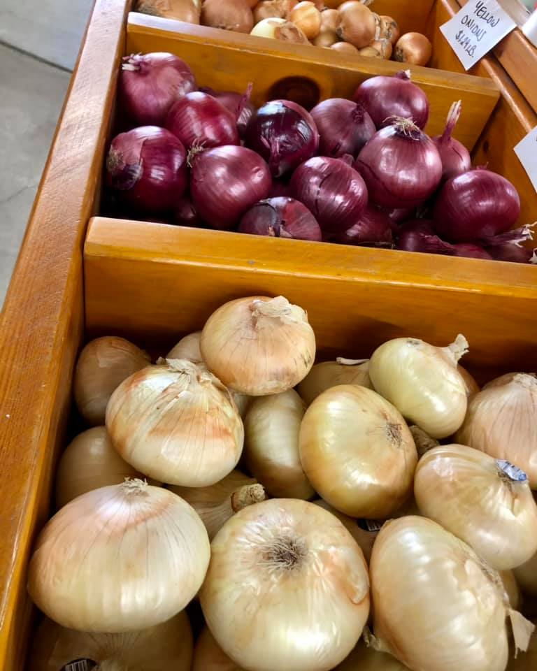 A wooden box filled with onions and red onions