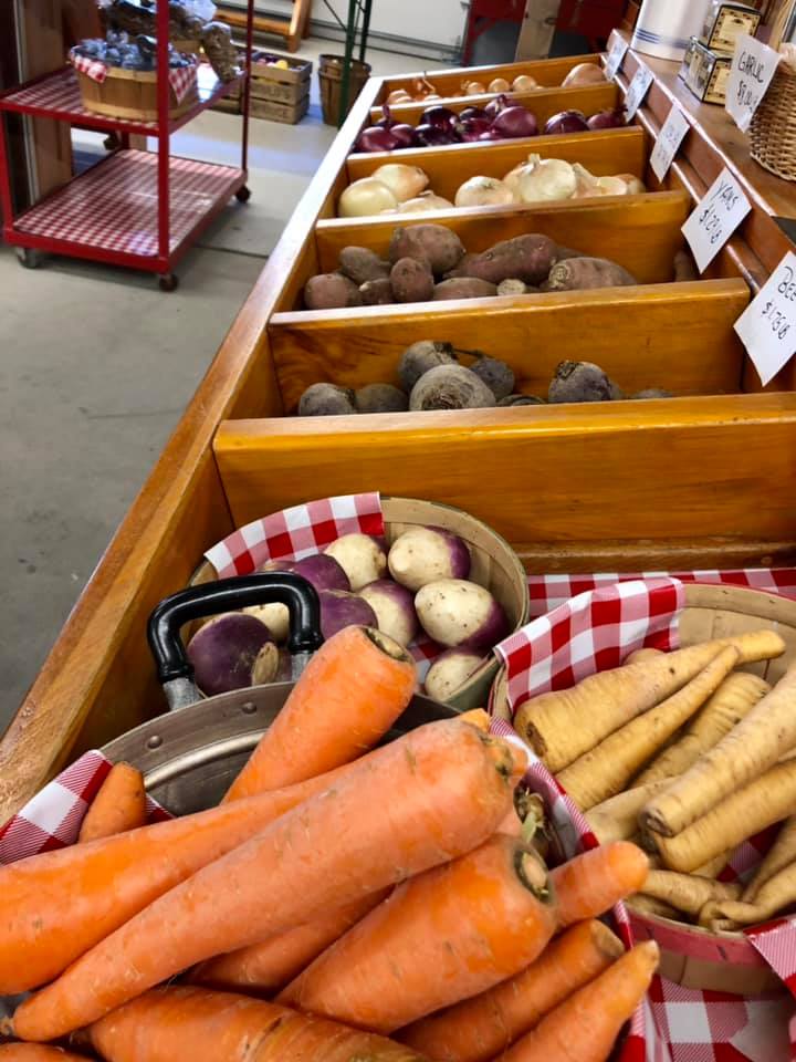 A bunch of carrots and potatoes are on a table in a store.