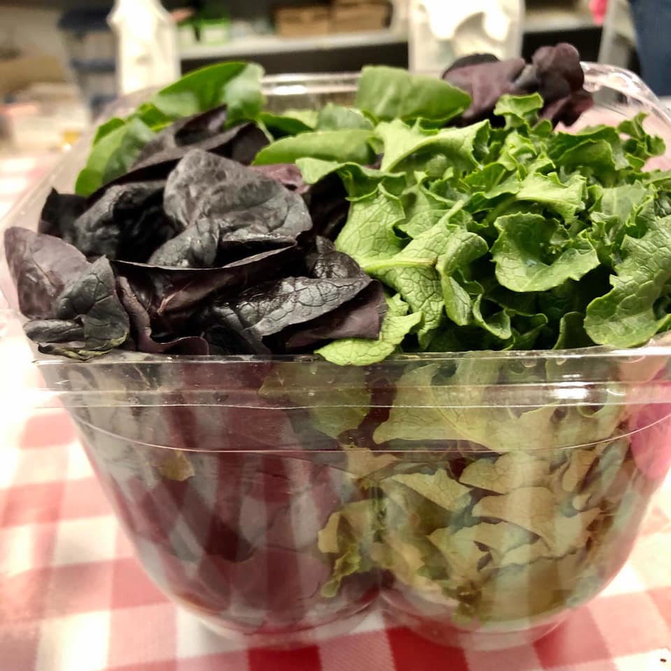 A plastic container filled with lettuce and purple leaves