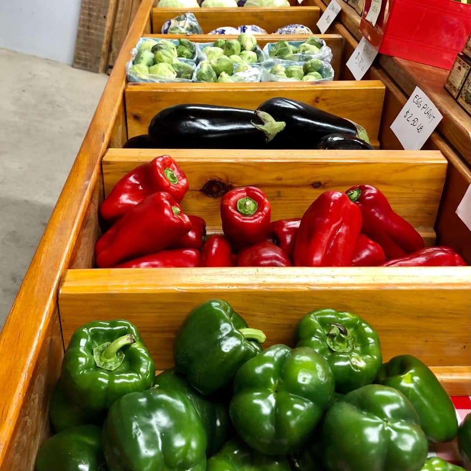 A row of wooden boxes filled with peppers and eggplant