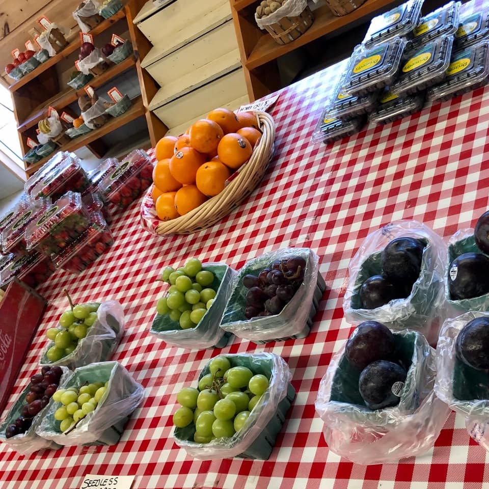 A table with a basket of oranges and grapes on it