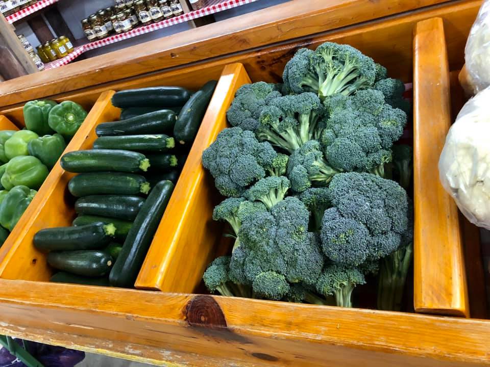 A wooden box filled with broccoli zucchini and peppers