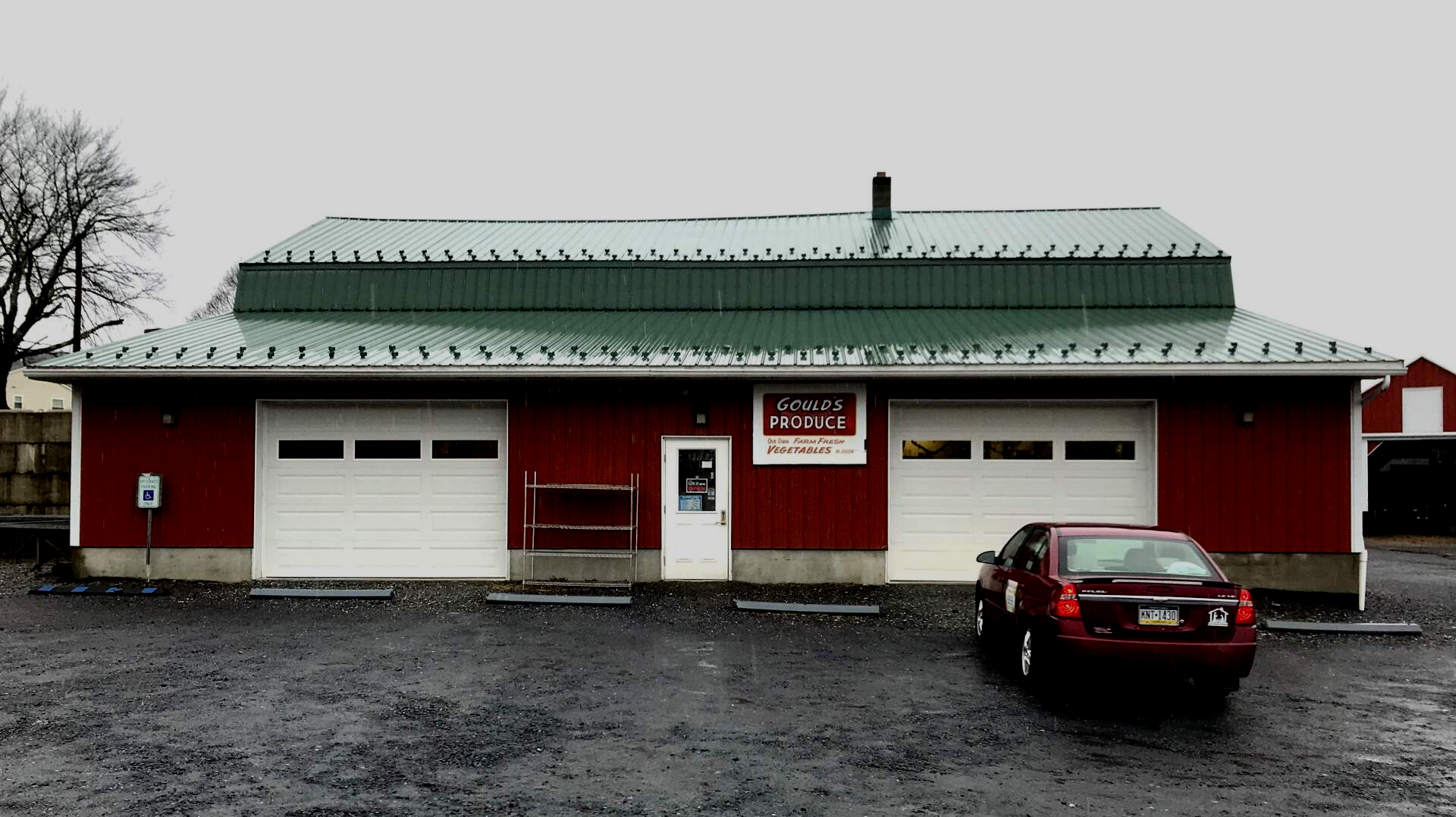 A red car is parked in front of a red building