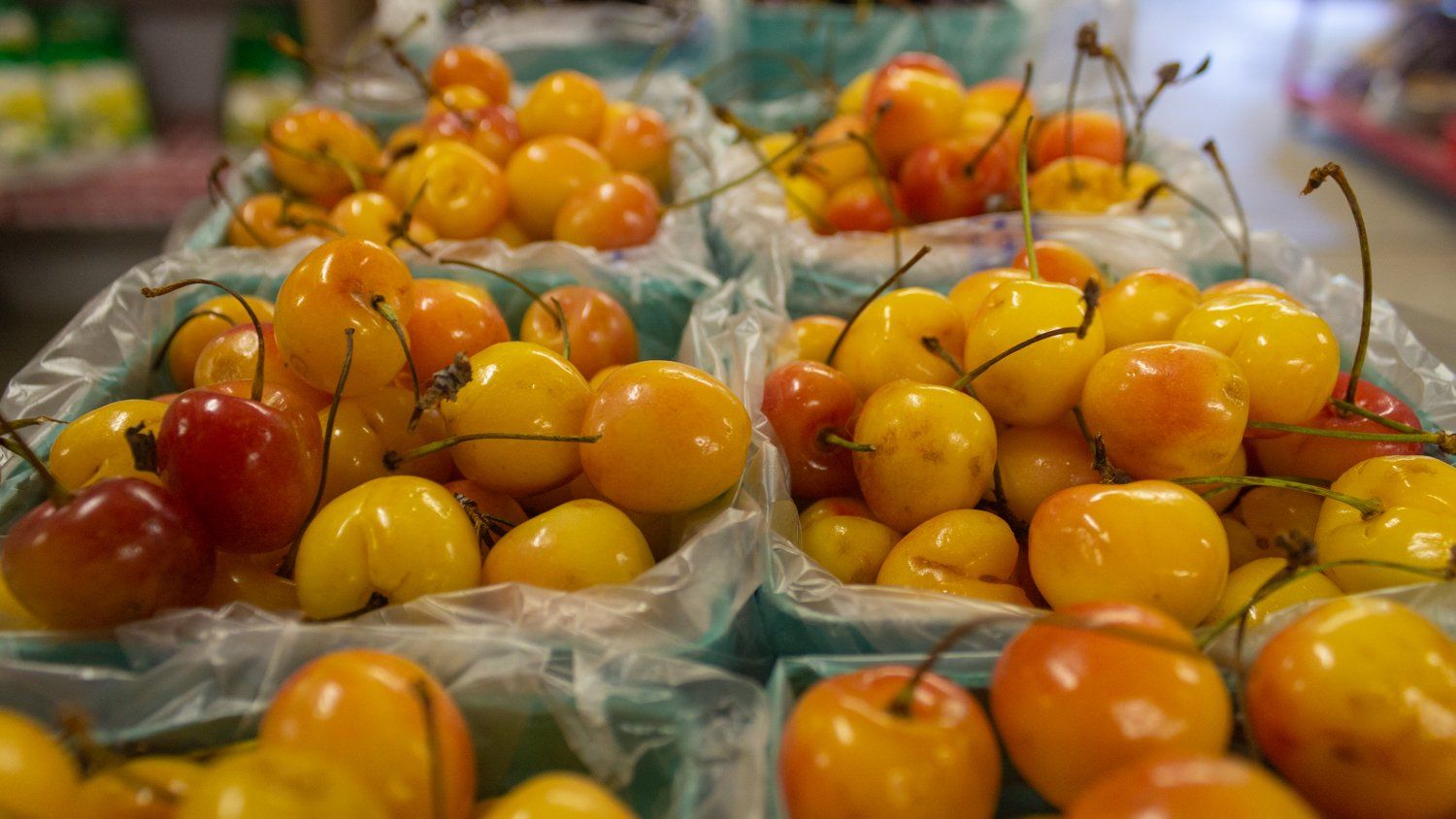 A bunch of yellow cherries in plastic bags on a table.