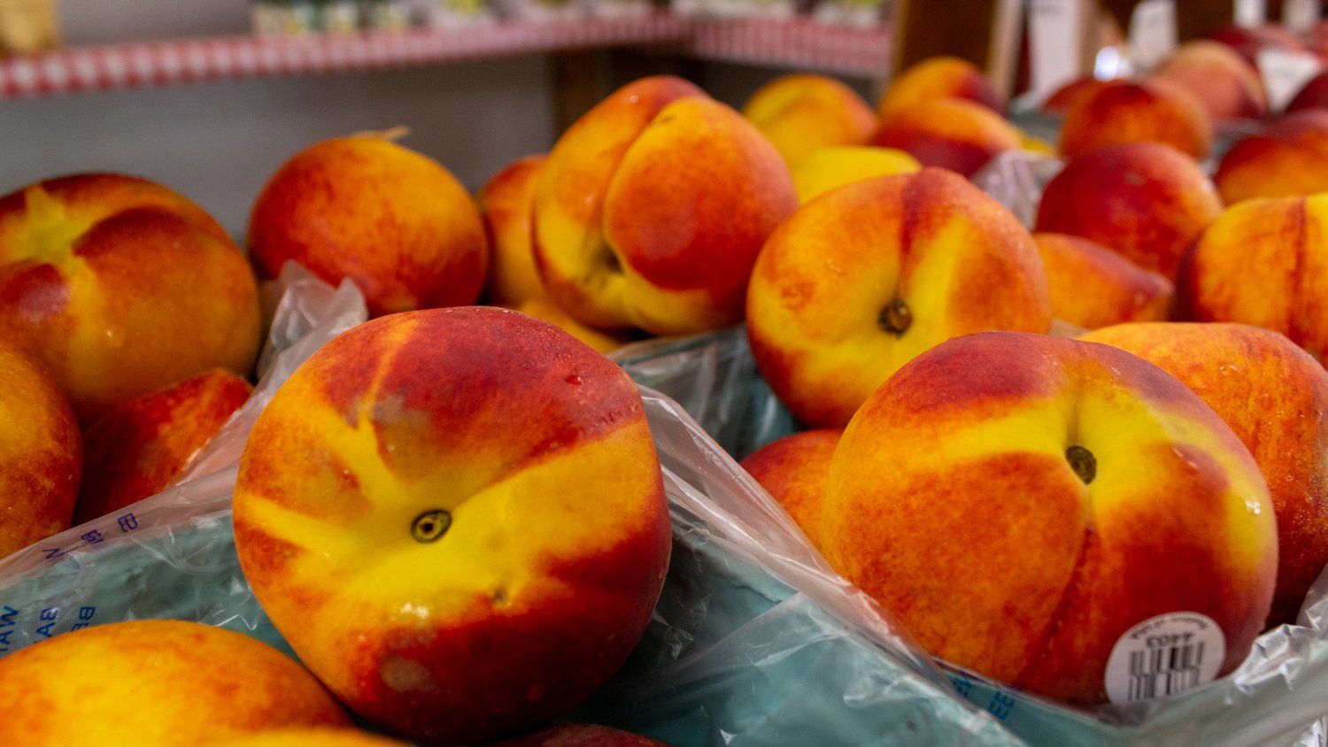 A bunch of peaches are sitting on top of each other on a table.