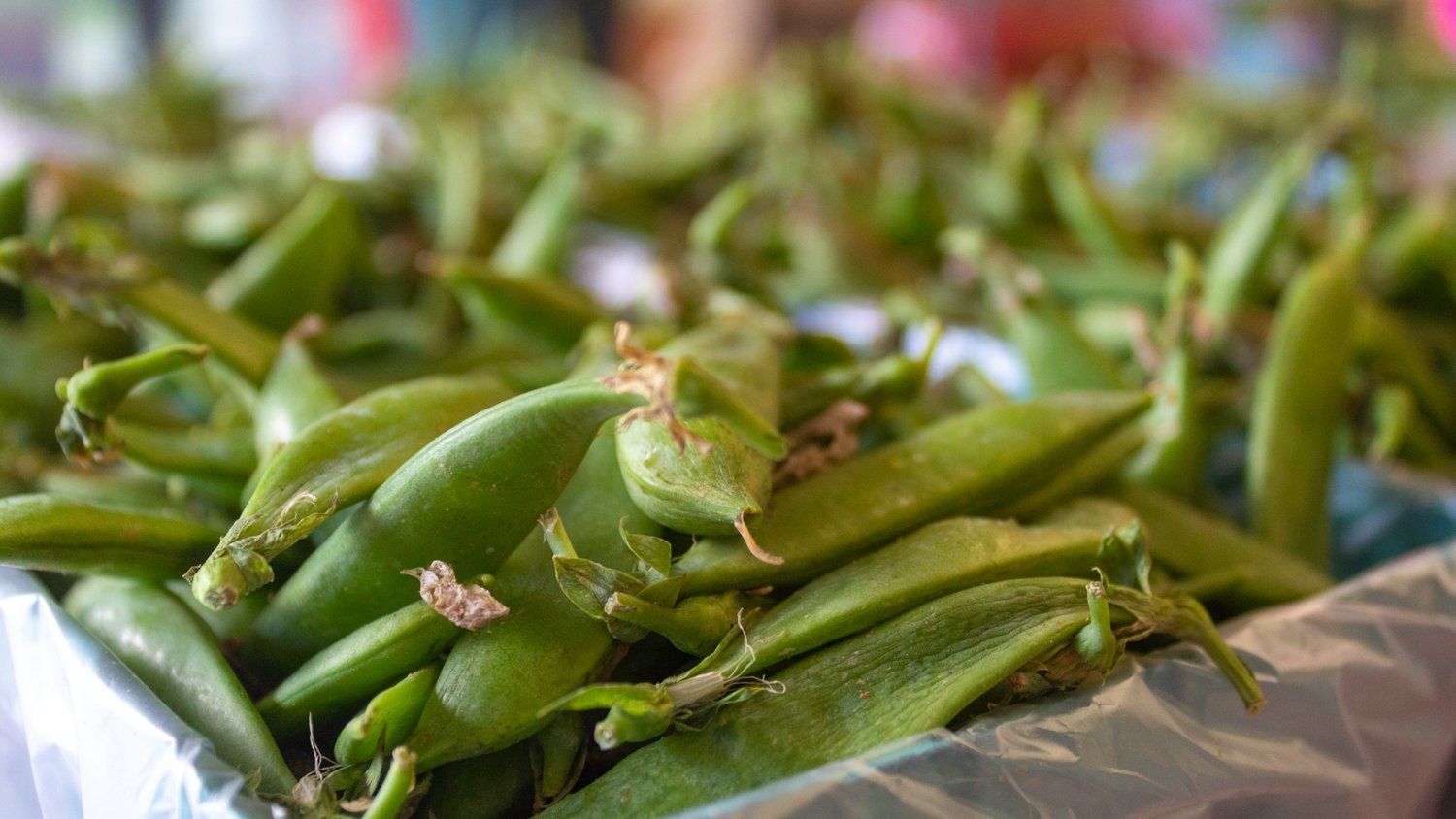 A bunch of green peas in a plastic bag on a table.