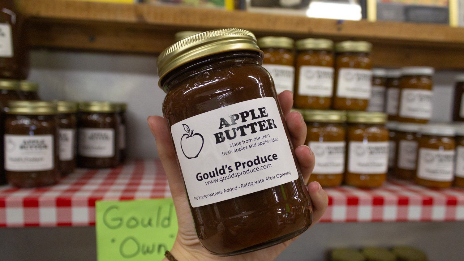 A person is holding a jar of apple butter in their hand.