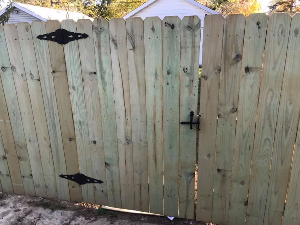 A wooden fence with a gate and a house in the background