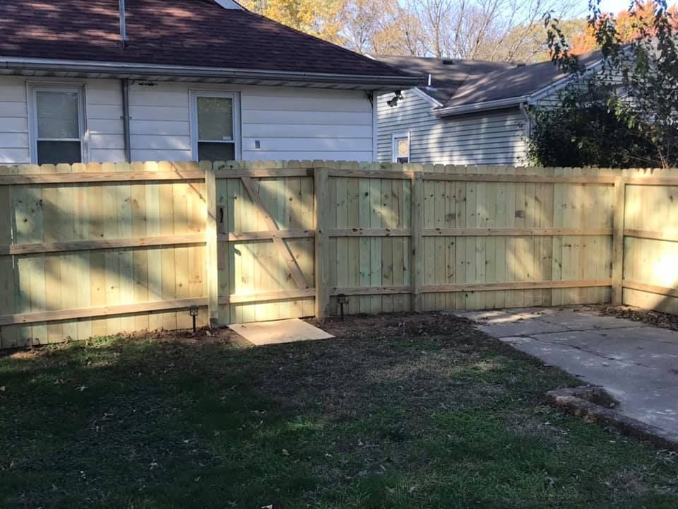 A wooden fence is in the backyard of a house.