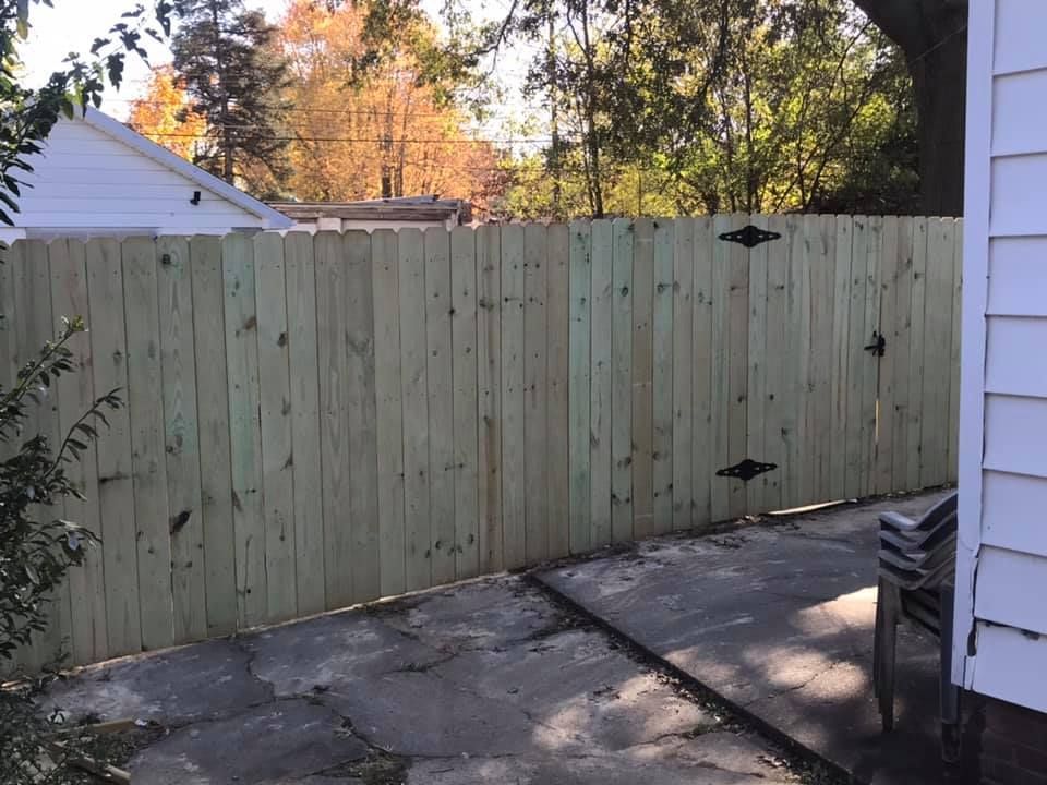 A wooden fence with a gate in the backyard of a house.