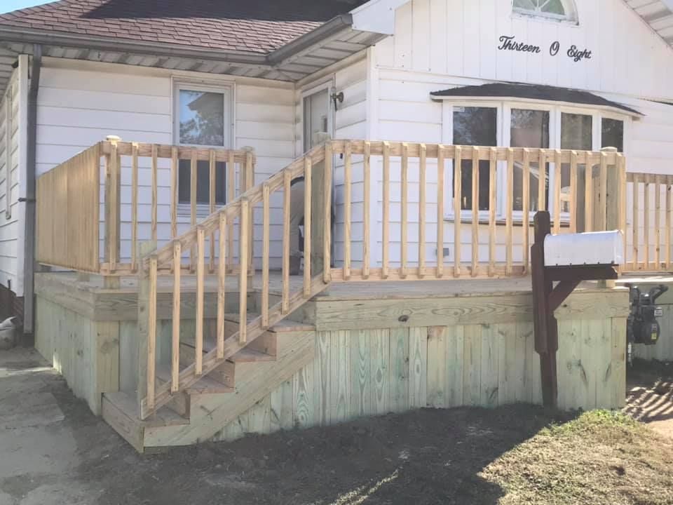 A white house with a wooden deck and stairs