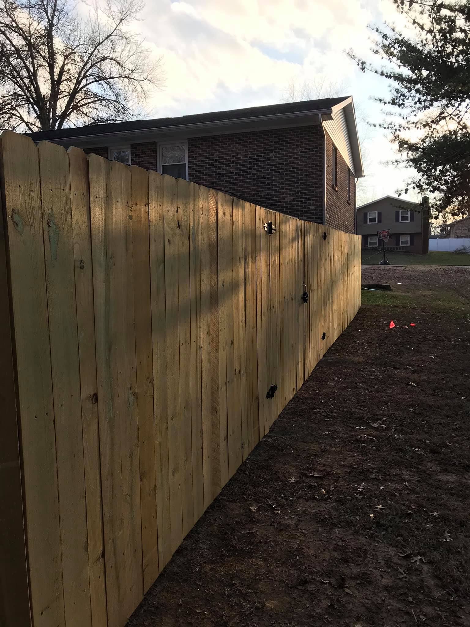 A wooden fence is sitting in front of a house.