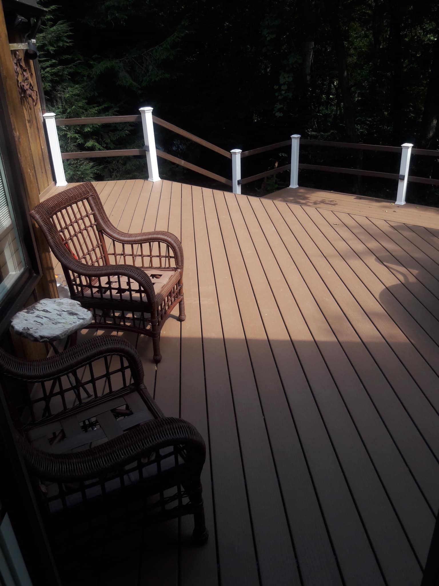 A wooden deck with wicker chairs and a table
