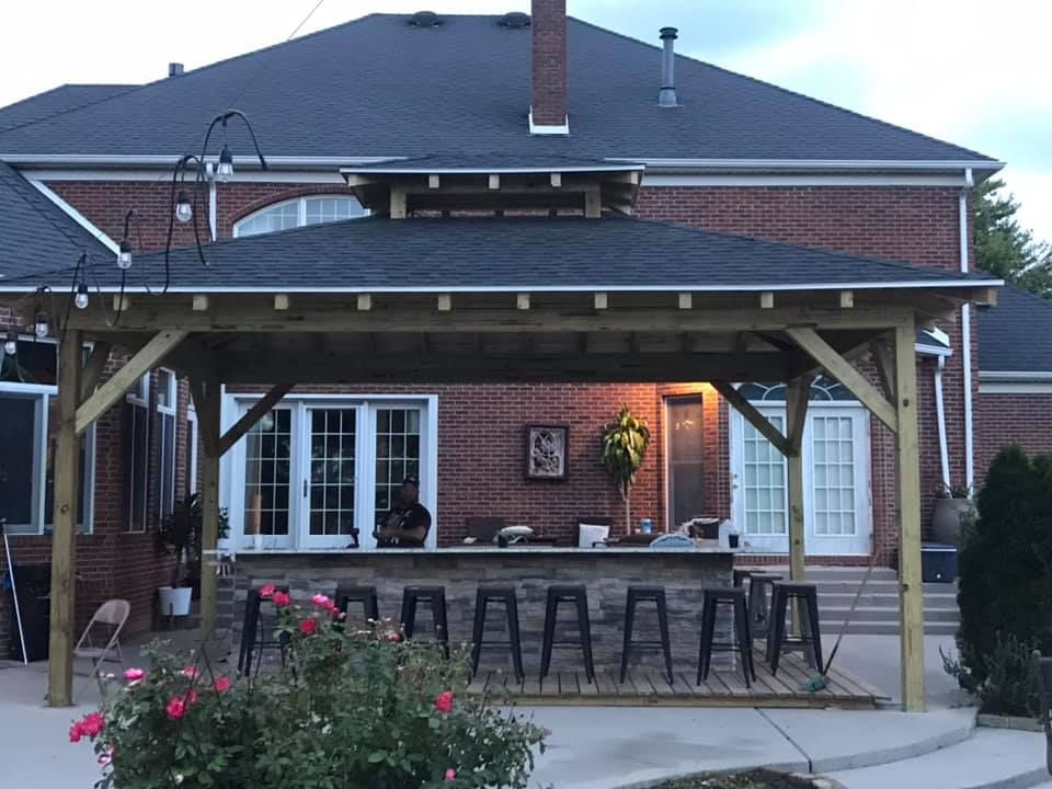 A brick house with a wooden gazebo in front of it