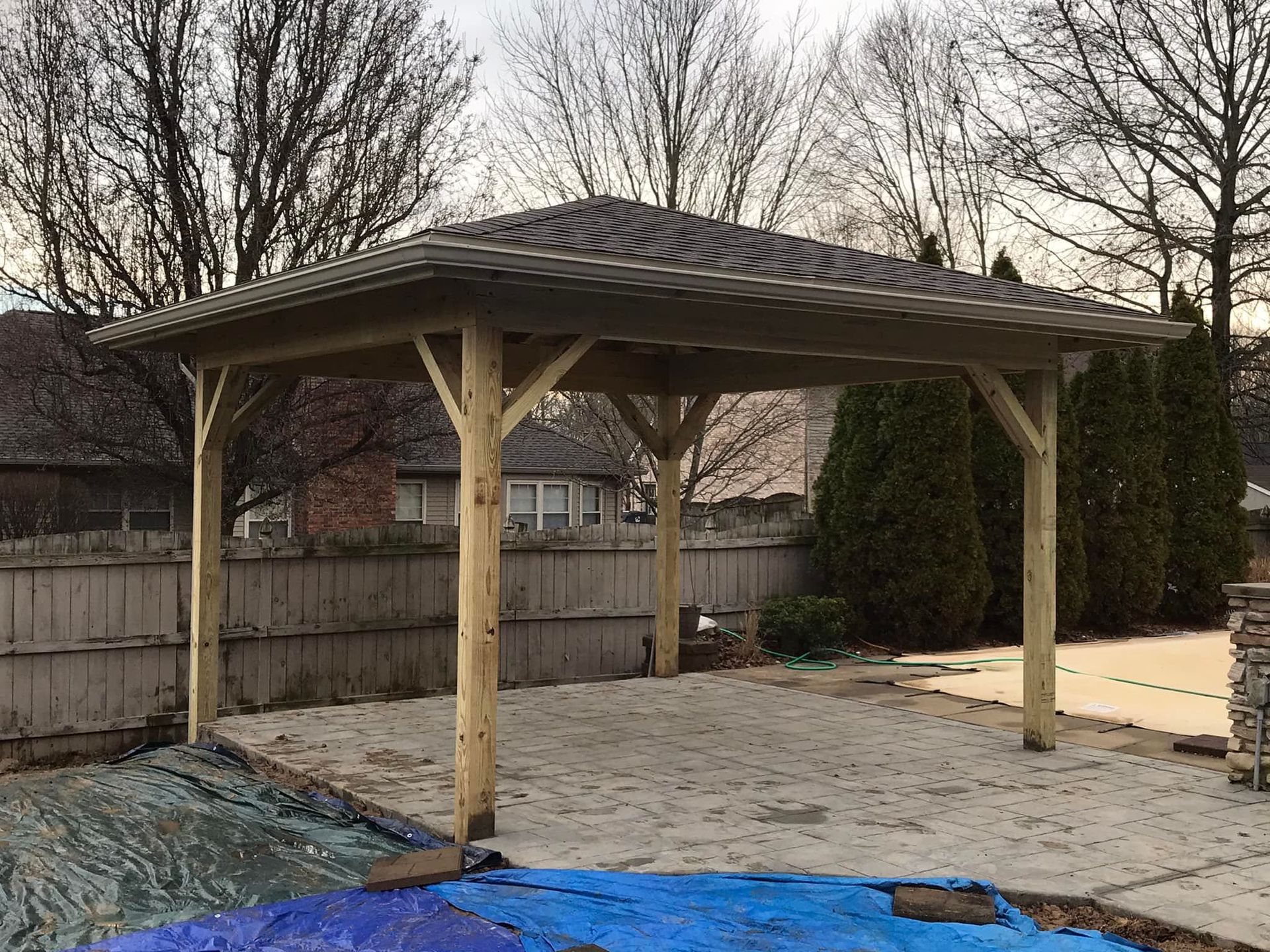 A wooden gazebo is sitting next to a pool in a backyard.