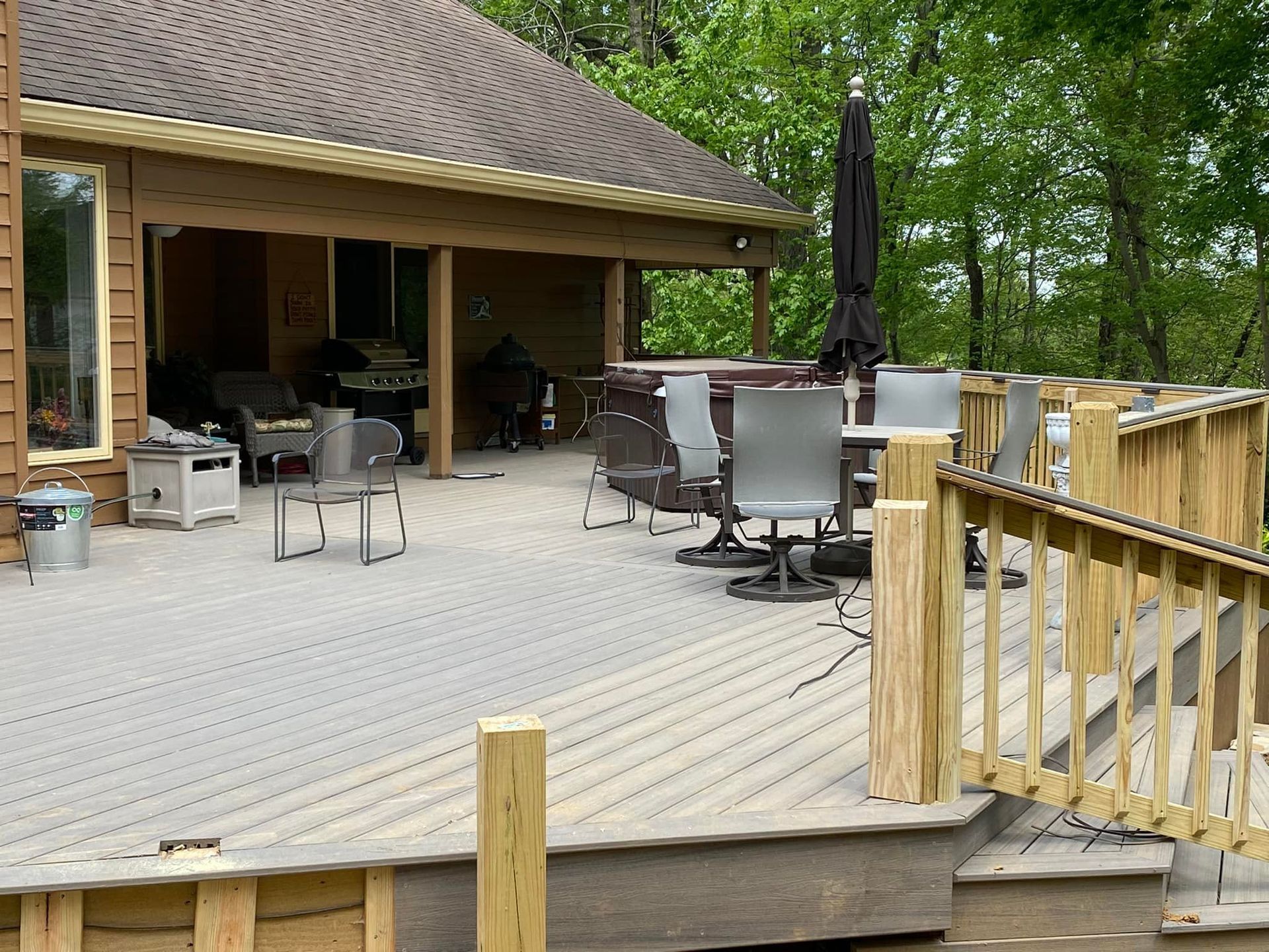 A wooden deck with chairs and umbrellas in front of a house