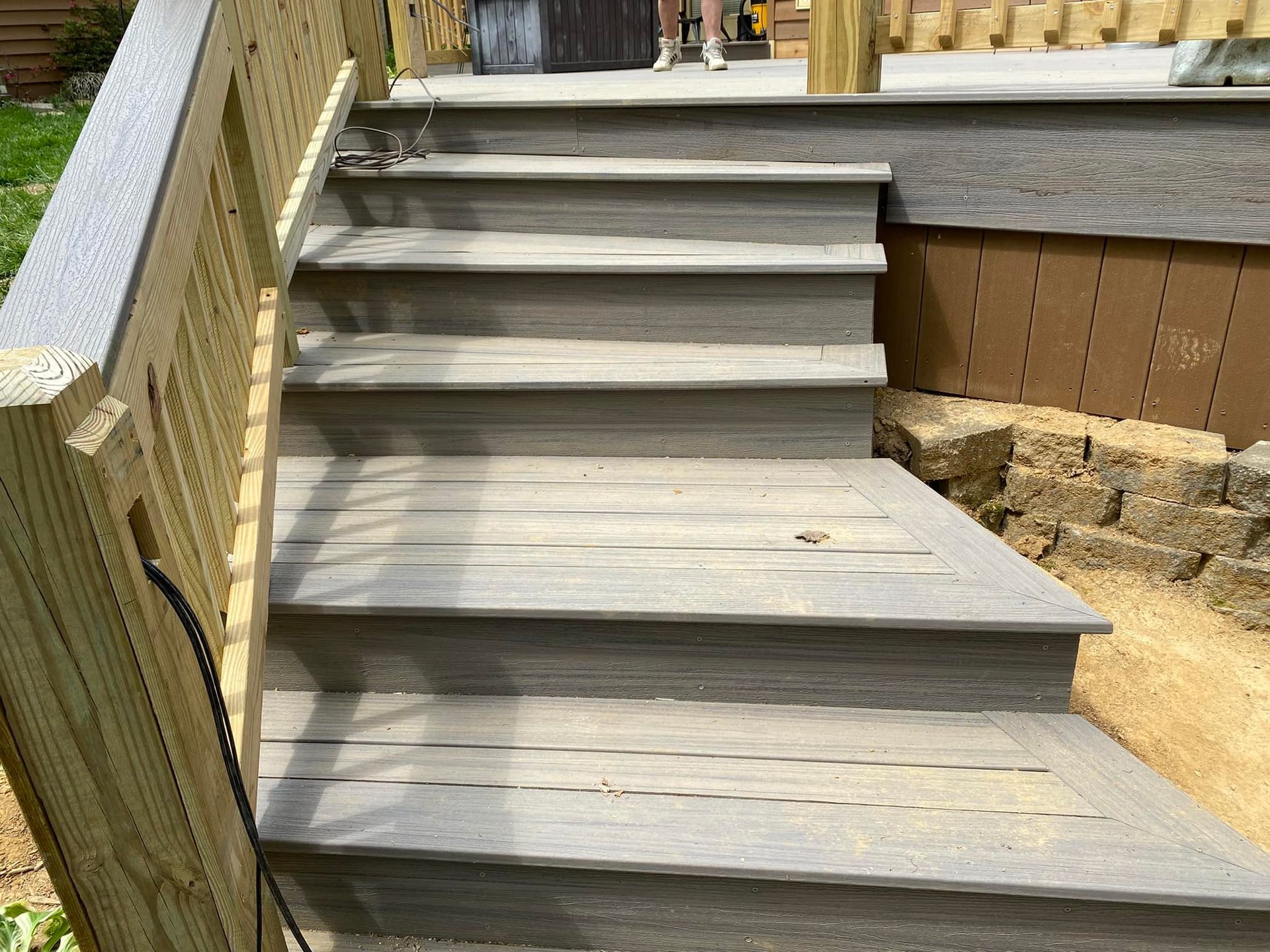 A wooden deck with stairs leading up to it and a wooden railing.
