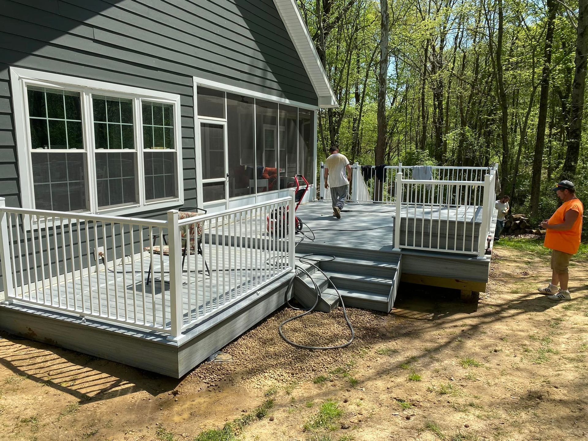 A man is standing in front of a house with a screened in porch.