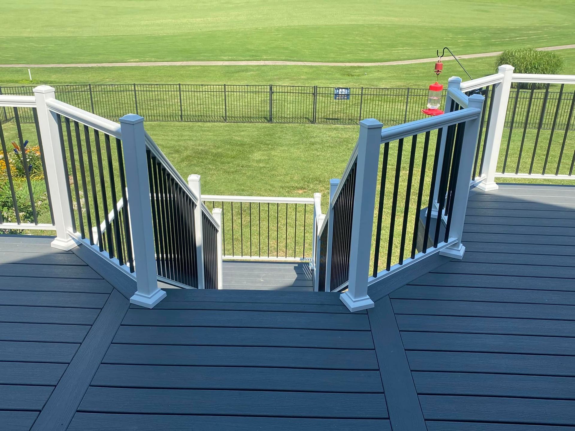 A deck with stairs leading up to a grassy field.