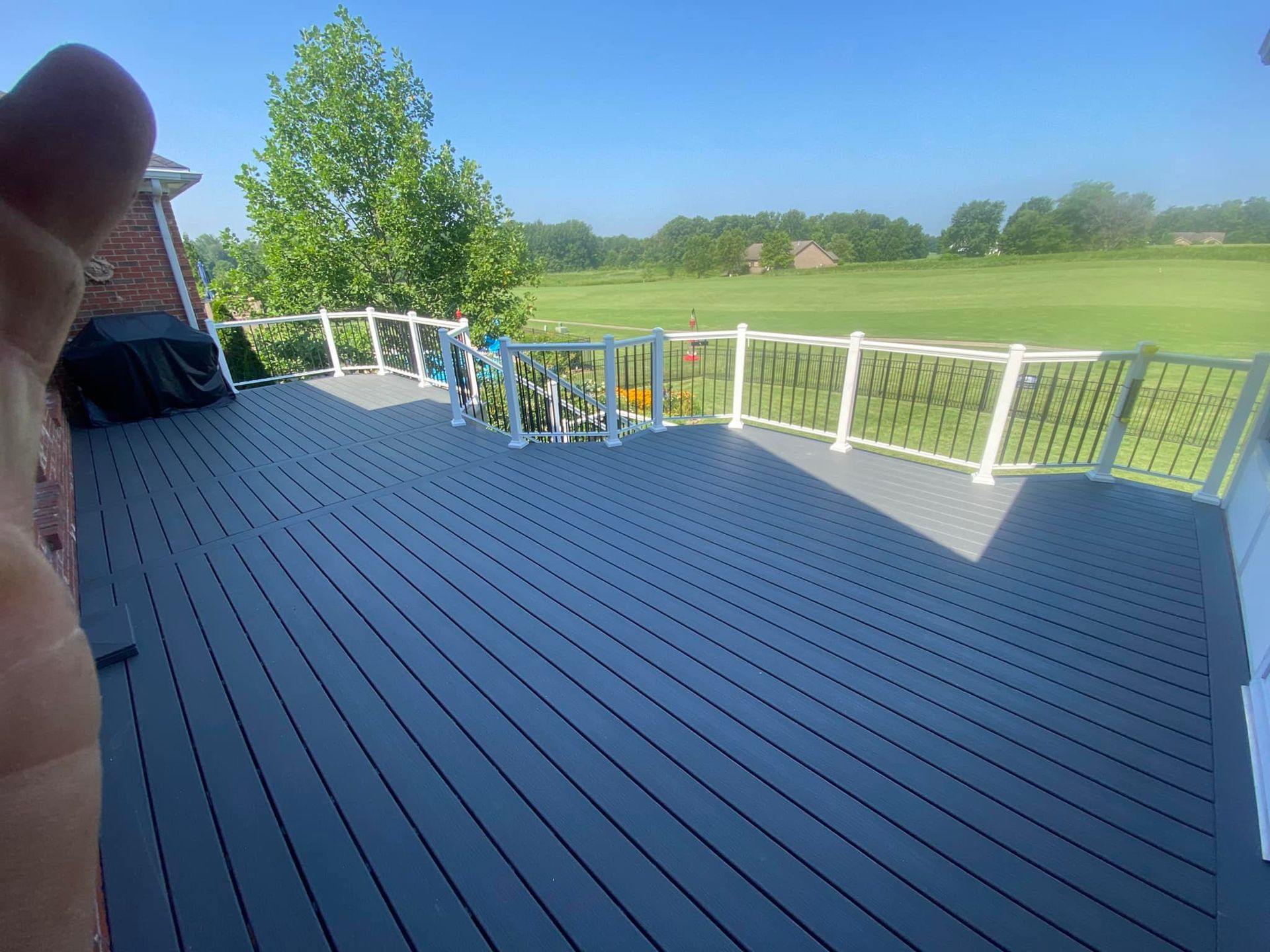 A person is standing on a deck with a view of a golf course.