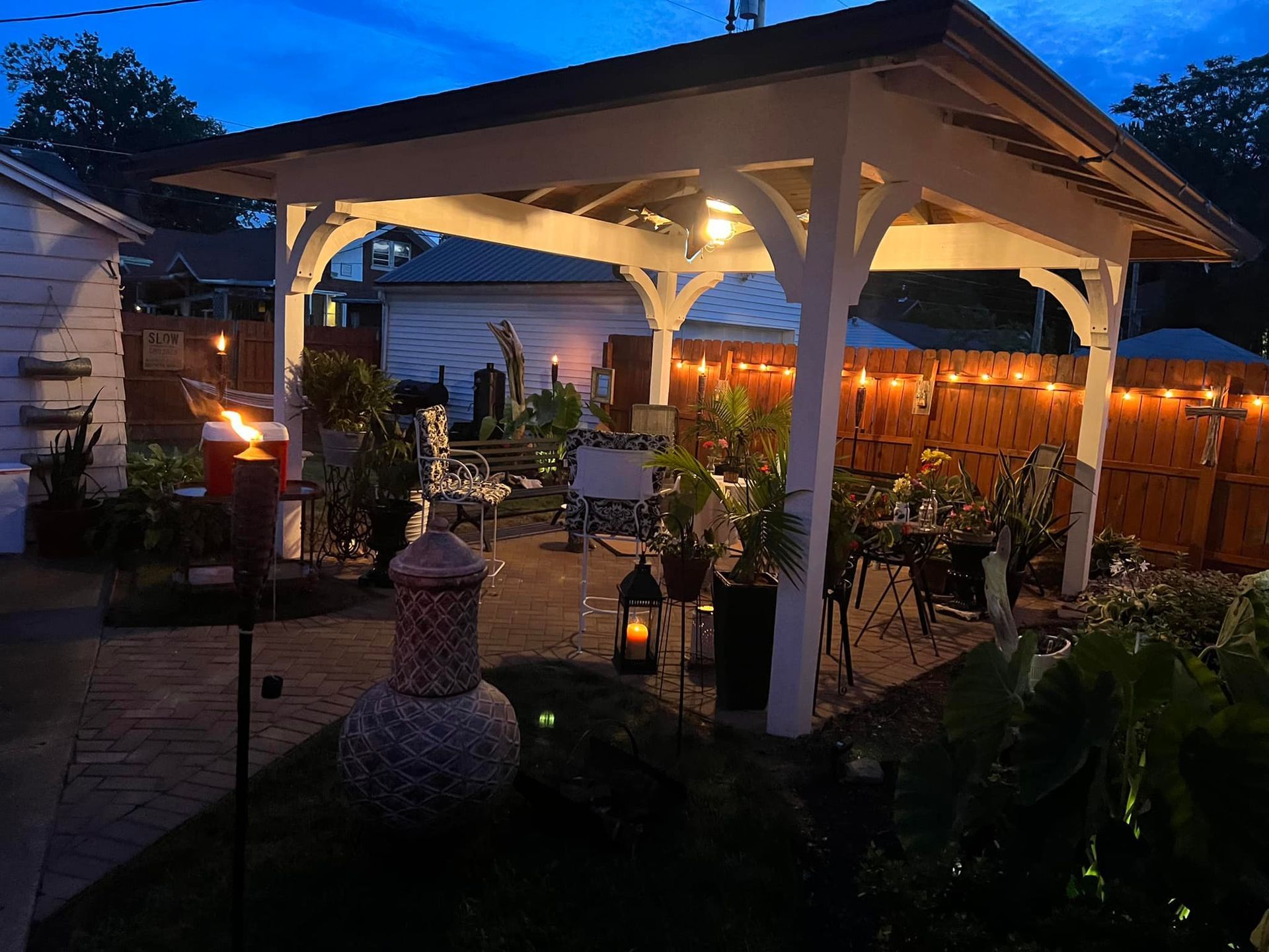 A gazebo is lit up at night in a backyard.